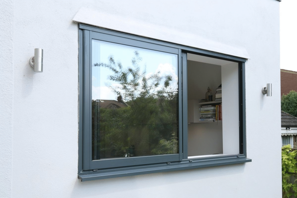 Pemasangan jendela sliding custom dengan rangka aluminium dan kaca lebar pada rumah modern minimalis