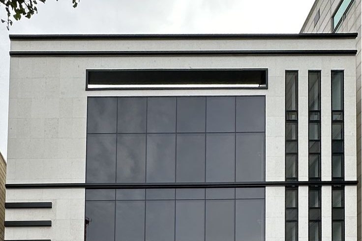 Desain fasad gedung modern dengan kombinasi kaca, panel aluminium, dan pencahayaan eksterior yang menonjolkan karakter bangunan.