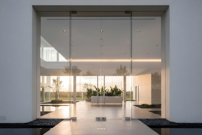 Pintu kaca tempered frameless minimalis untuk area pintu masuk kantor dengan engsel lantai stainless steel.