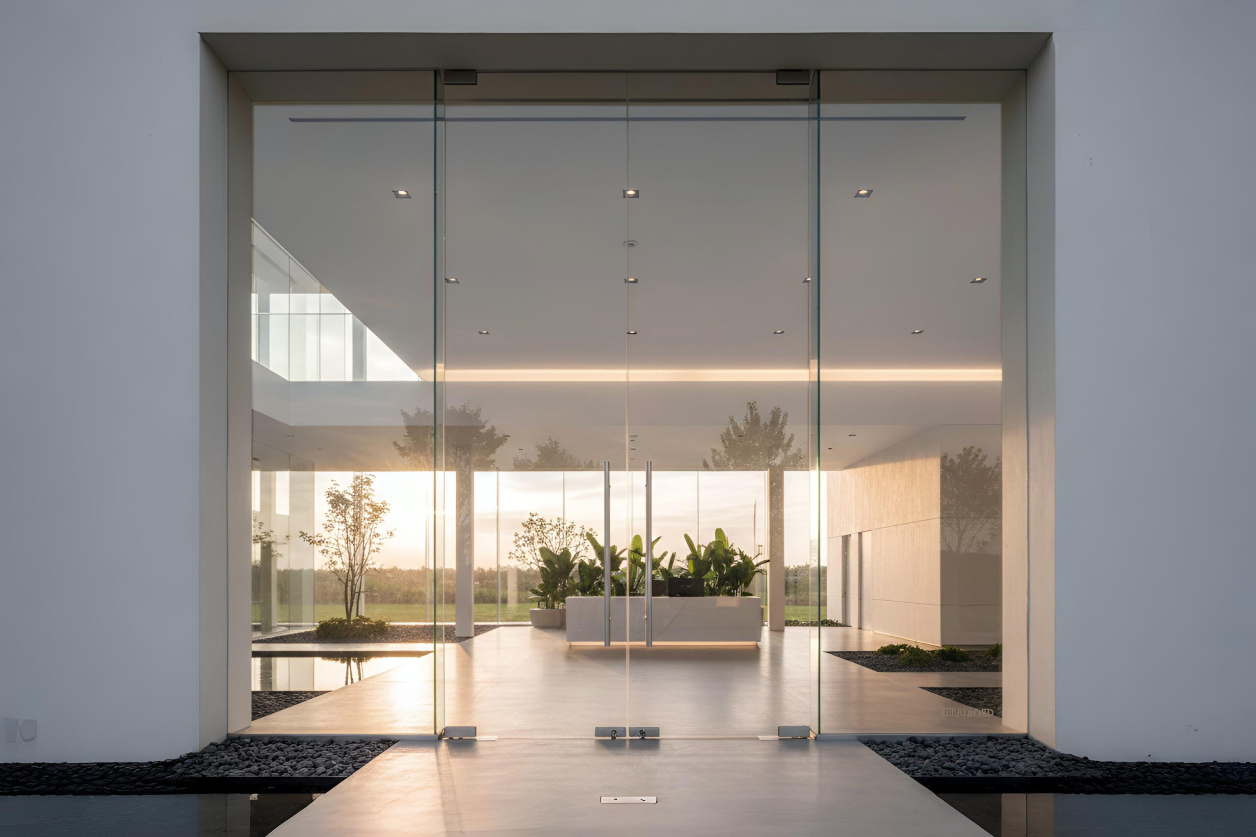 Pintu kaca tempered frameless minimalis untuk area pintu masuk kantor dengan engsel lantai stainless steel.